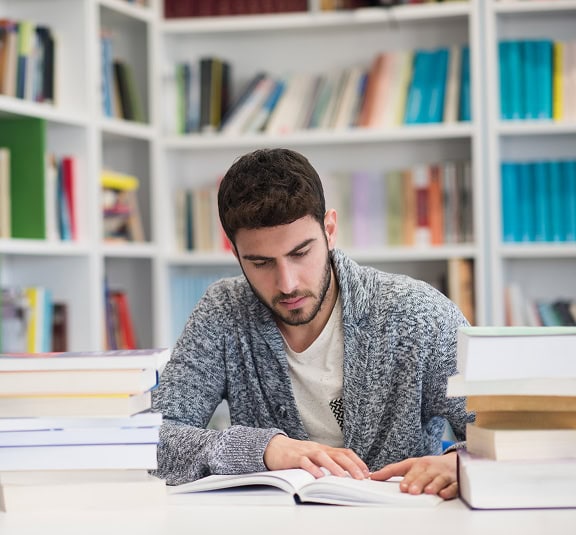 Estudiante estudiando en una biblioteca con muchos libros, en un ambiente de aprendizaje personaliza.